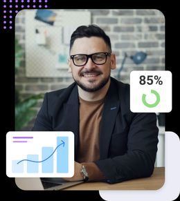 Smart casual man sat at desk with laptop surrounded by generic graphs